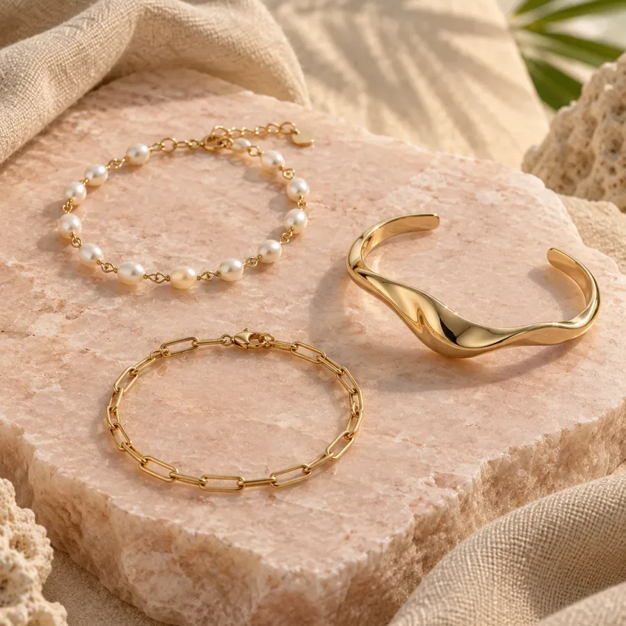Three gold-tone bracelets in pearl, link and sculptural cuff styles