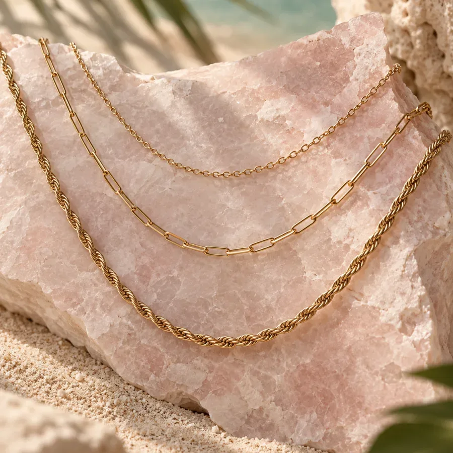 Three gold-tone chains in fine, paperclip and twisted styles on pale pink stone